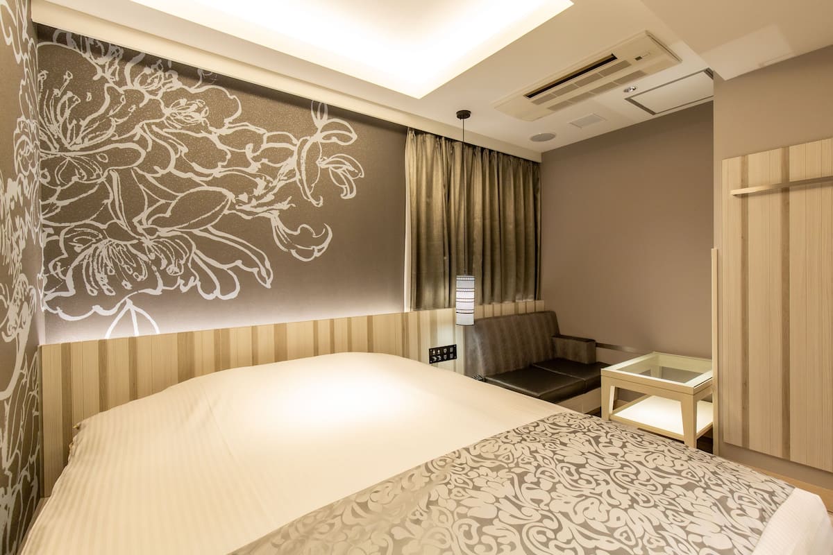 Quarto de hotel com uma cama grande, uma pequena mesa, um sofá e um guarda-roupa.