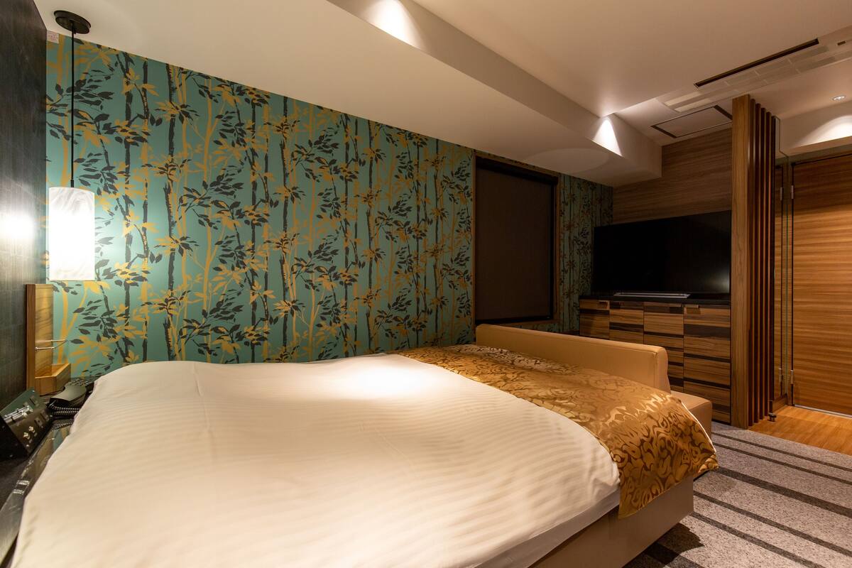 Quarto de hotel com uma cama grande, uma televisão e um guarda-roupa de madeira.