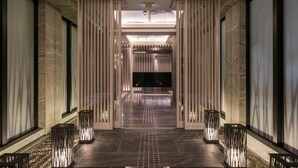 Un pasillo moderno de hotel con un diseño elegante, que presenta un camino central, iluminación decorativa y un mostrador de información visible.