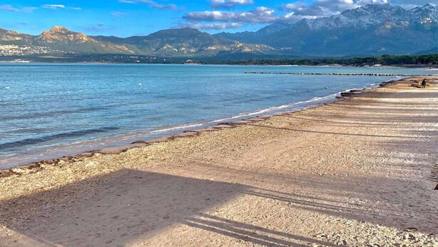 A beach with pebbles, a clear sky, and mountains in the background. - Cozy 1BR Apartment with Parking, 700m from Calvi Beach (Calvi)