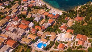 An aerial view of a coastal residential area with houses, a beach, and a swimming pool. - Villa Berry (Corfu)