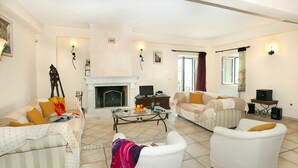 A living room with a fireplace, two sofas, a coffee table, and a television. - Villa Berry (Corfu)