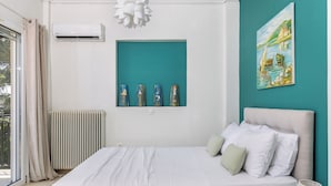 Un dormitorio con cama, ventana, equipo de aire acondicionado, radiador y un cuadro en la pared.