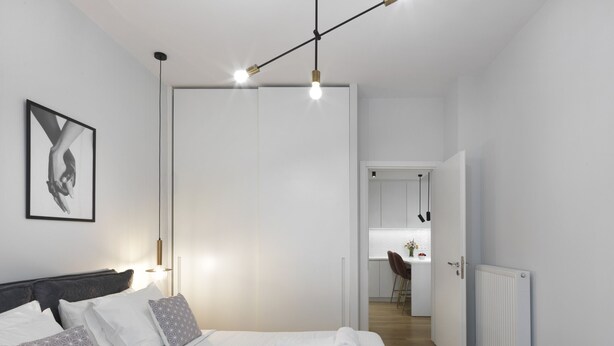 Ett modernt hotellrum med en snyggt bäddad säng, ett inramat konstverk på väggen och utsikt över den intilliggande matsalen.