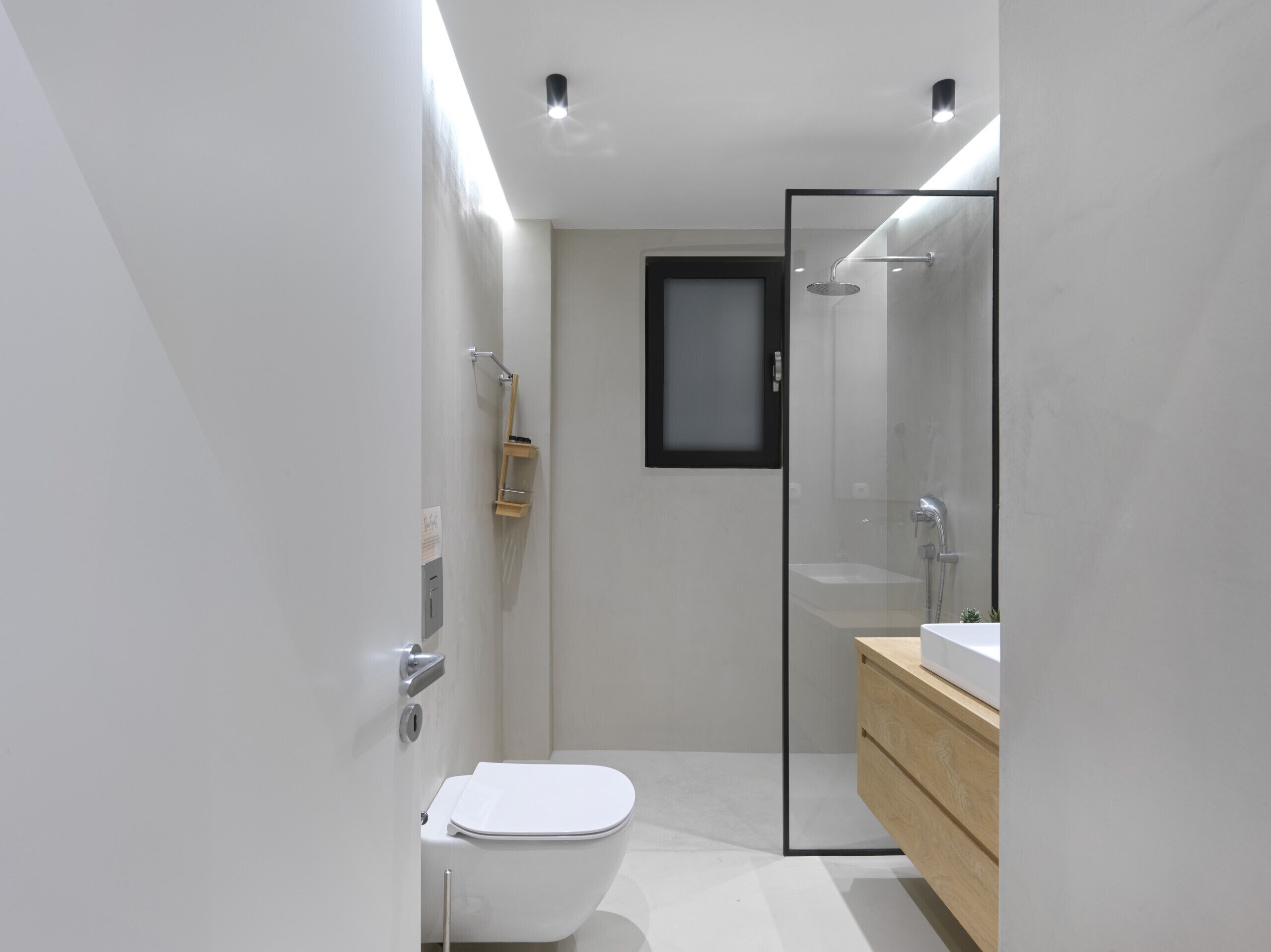 A modern bathroom with a toilet, a glass shower enclosure, and a wooden vanity.