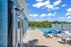 A pool area with lounge chairs, a clear sky, and a view of the surrounding greenery.