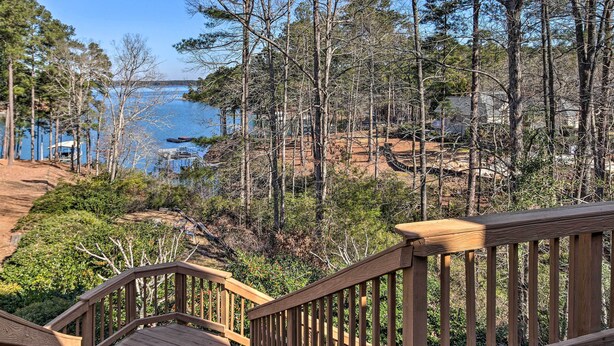 Une terrasse en bois donnant sur un lac, avec des arbres et une rive rocheuse.