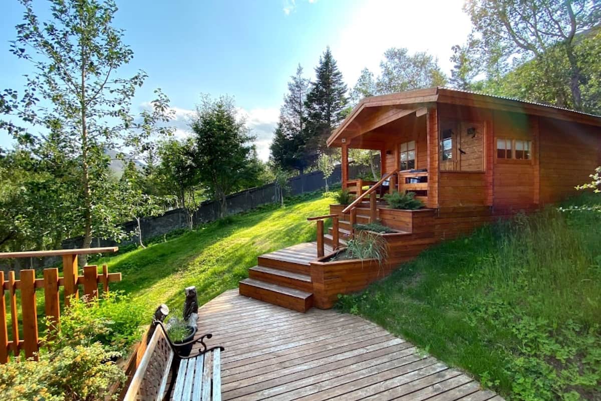 A wooden cabin with a wooden deck and stairs leading to a porch.