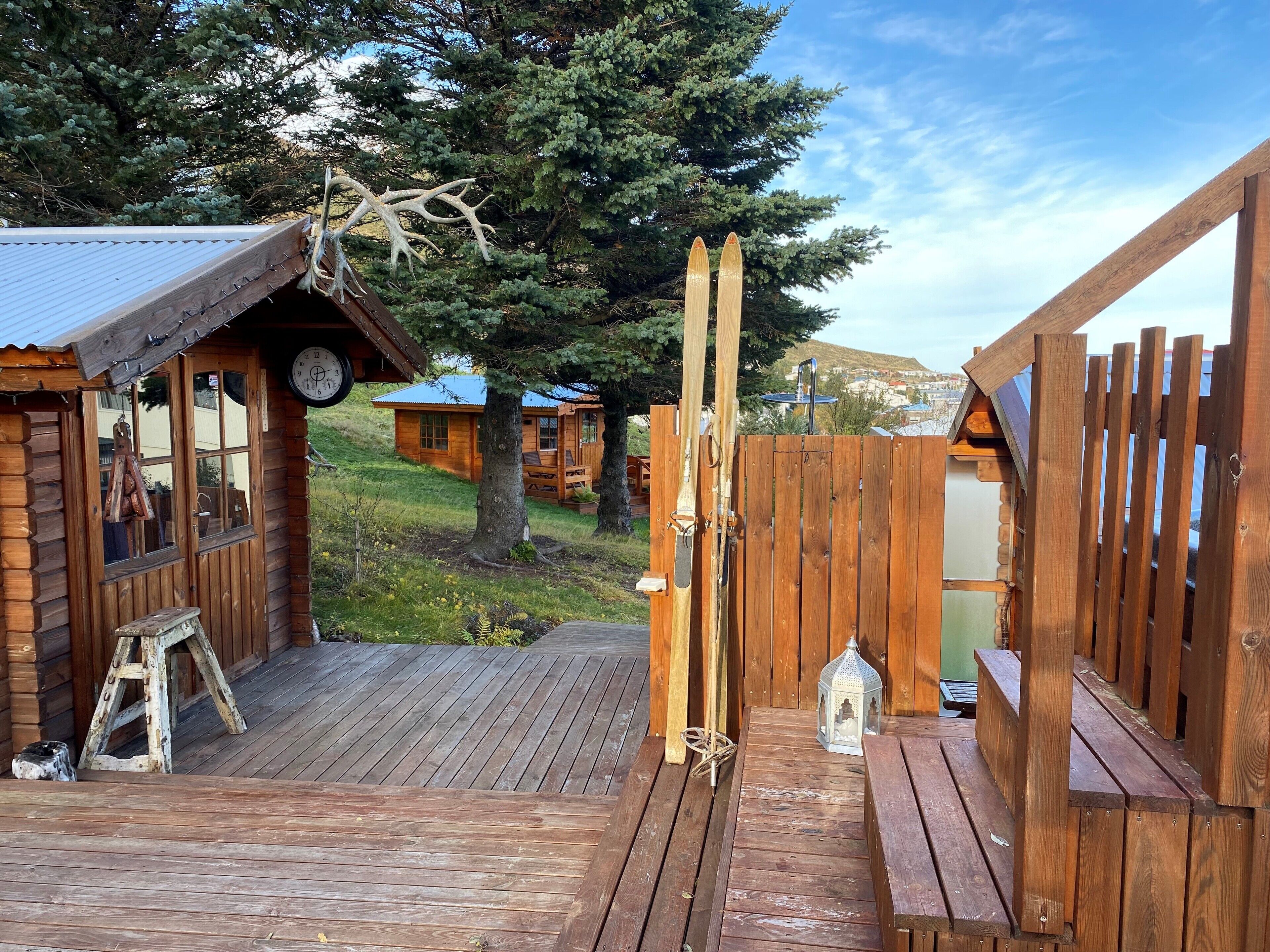A wooden cabin with a porch, a clock, and a wooden fence.