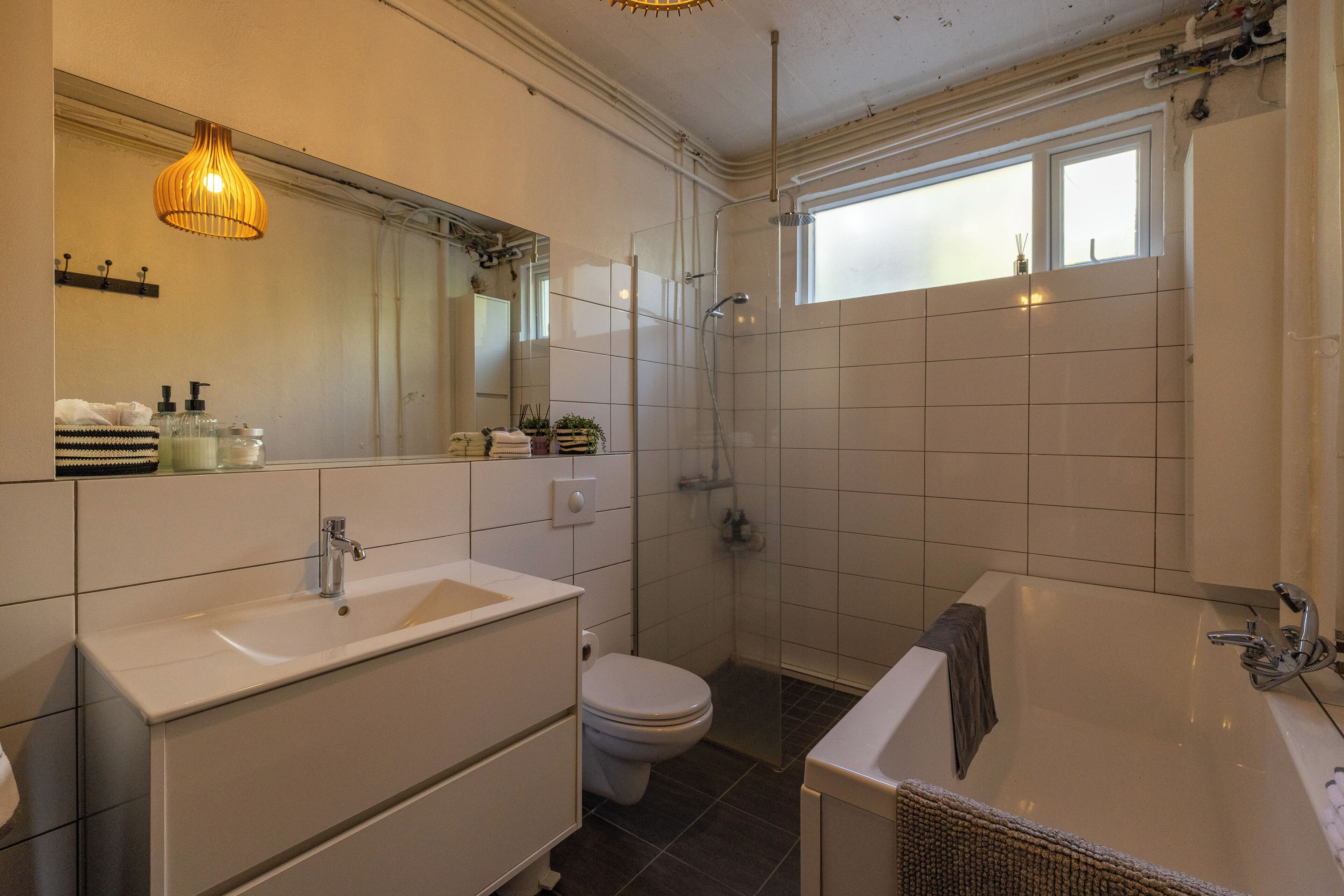A modern bathroom with a sink, toilet, shower, and bathtub.