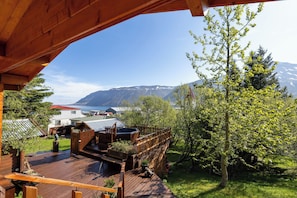 A wooden deck with a hot tub, a wooden fence, and a view of mountains and a lake.
