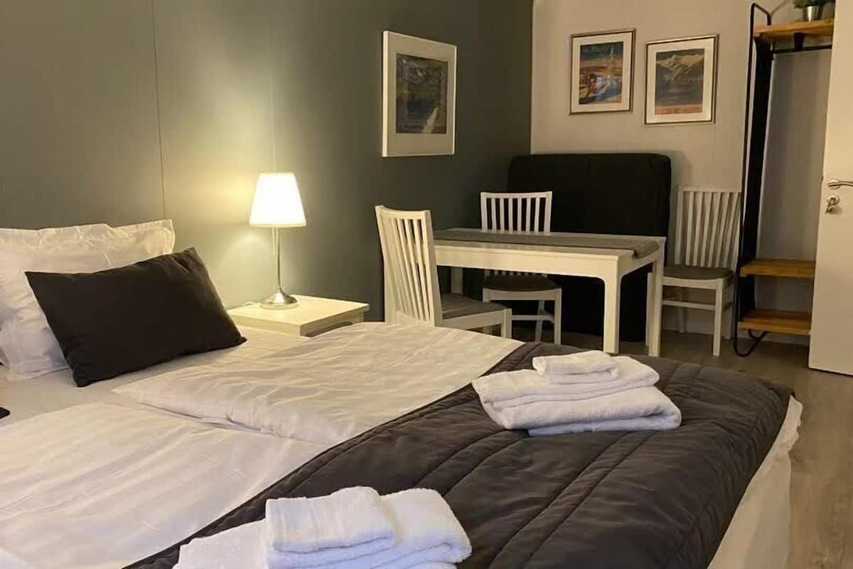 A hotel room with two beds, a desk, and a chair.