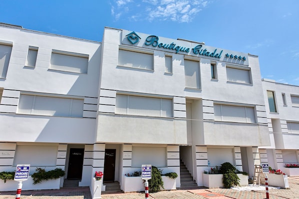 Un edificio blanco con un letrero que dice "Boutique Citadel" y una señalización que indica estacionamiento reservado.