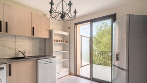 A modern kitchen with a dishwasher, a built-in oven, and a large window with a view of the outdoors. - Demi Villa Dans u Quartier Résidentiel Avec Accès Privé à la Plage (Olmeto)