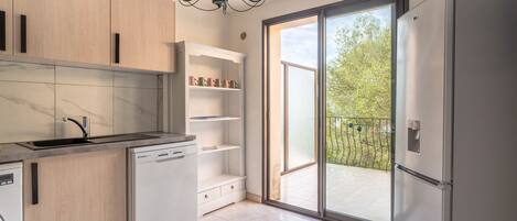 A modern kitchen with a dishwasher, a built-in oven, and a large window with a view of the outdoors.