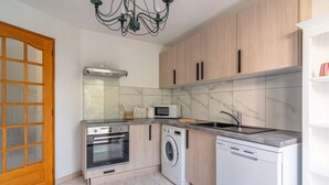 A compact kitchen with a built-in oven, microwave, washing machine, and dishwasher. - Demi Villa Dans u Quartier Résidentiel Avec Accès Privé à la Plage (Olmeto)