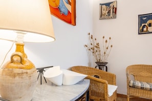 A room with a lamp, wicker chairs, a table, and wall art.