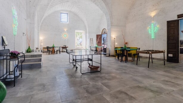 Une pièce spacieuse avec un haut plafond en arc de cercle, une table centrale et une porte située à droite.