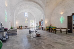 Une pièce spacieuse avec un haut plafond en arc de cercle, une table centrale et une porte située à droite.