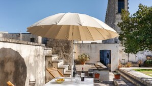 Une terrasse extérieure avec une table, des chaises, un grand parasol et une plante en pot.