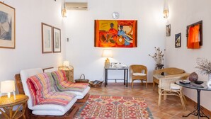 Un salon chaleureux avec un canapé, des fauteuils, une table et un tapis aux couleurs vives.
