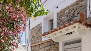 Une rue étroite bordée de murs en pierre, avec une porte blanche et des plantes en pot.