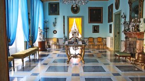 A room with a checkered floor, a chandelier, and a statue of a woman. - HomeMuseum (Palermo)