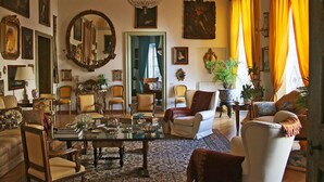 A spacious living room with a large chandelier, multiple armchairs, a coffee table, and various decorative items. - HomeMuseum (Palermo)