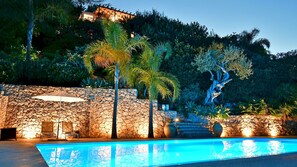 A swimming pool with a stone wall and palm trees, a stone wall with a door, and a staircase leading up to a building. - Villa Karin 7 in Taormina (Taormina)