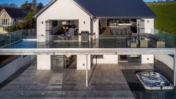Enjoy an outdoor space with a pool and hot tub, a kitchen, dining area, living room, and balcony.