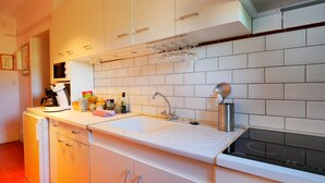 Eine moderne Küche mit weißen Schränken, einer doppelten Spüle und einem Weinkühlschrank über der Arbeitsplatte.