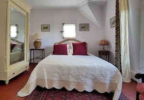 Ein Schlafzimmer mit einem großen Bett, zwei Nachttischlampen, einem Spiegel und zwei gerahmten Bildern an der Wand.