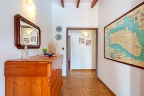 A hallway with a wooden dresser, a large map on the wall, and a mirror.