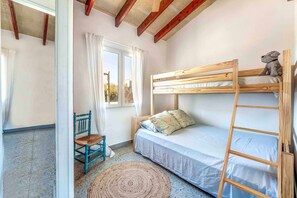 Um quarto acolhedor com uma cama de solteiro, uma cadeira, uma janela com cortinas e uma escada de madeira.