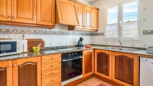 A kitchen with wooden cabinets, a microwave, a stove, and a sink.