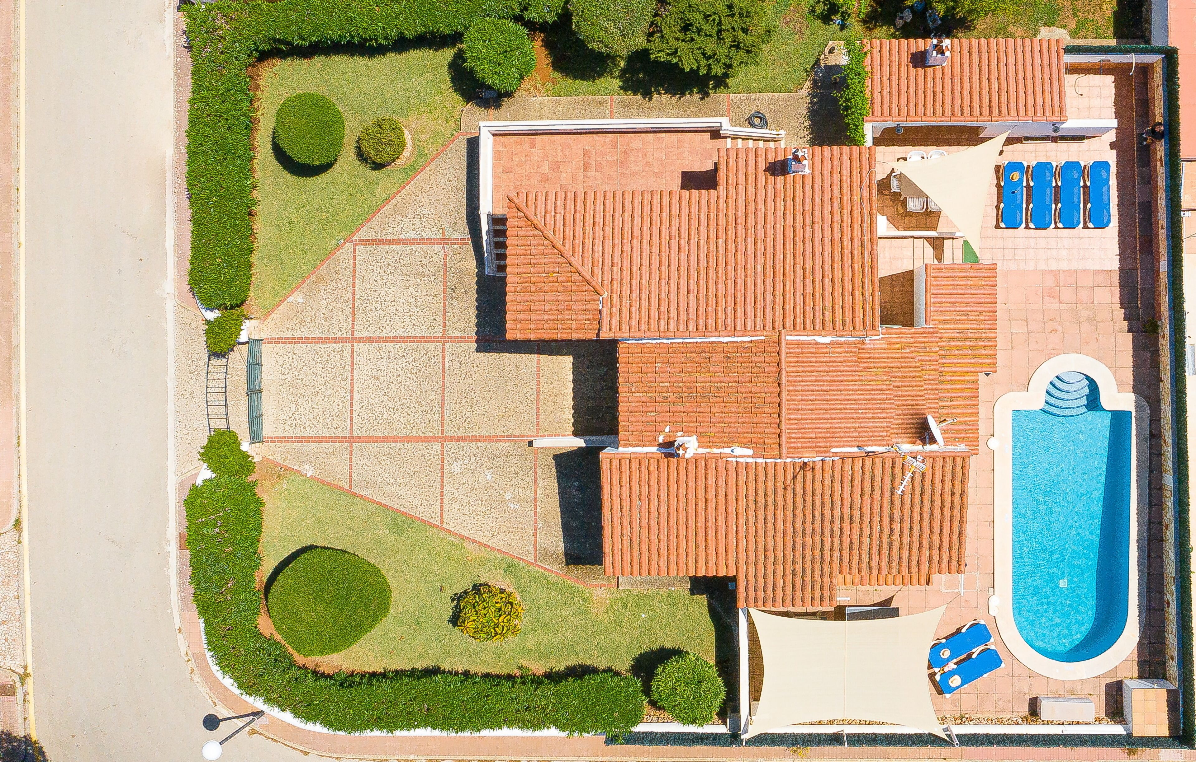 An aerial view of a property with a swimming pool, a covered patio area, and a landscaped garden.