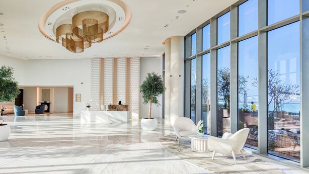 A spacious lobby with a marble floor, a reception desk, seating area, large windows, and a modern ceiling design. - Maison Privee - 5242 Emaar (Dubai)