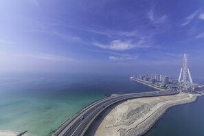 An aerial view of a coastal area with a bridge, a beach, and a cityscape.