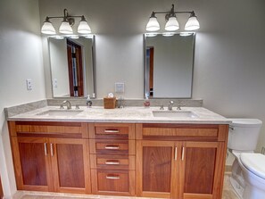 A bathroom with a double sink vanity, wooden cabinets, and a large mirror.