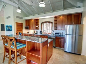 A modern kitchen with wooden cabinets, stainless steel appliances, and a granite island.