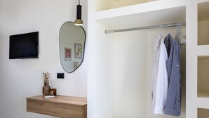 A modern bathroom with a wooden vanity, a mirror, a flat-screen TV, and a hanging clothes rack. - Kamara Apartments (Zakynthos)