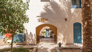 Un patio exterior con un camino de piedra que lleva a la entrada de un edificio, marcada con un número.