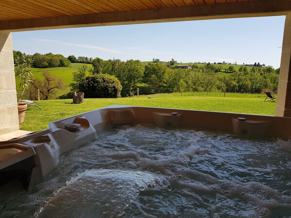 A hot tub with a view of a green landscape.