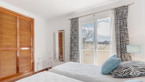 Habitación de hotel con dos camas, un balcón y vistas a la ciudad.