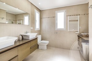 Une salle de bain moderne avec un grand lavabo blanc, des toilettes et un miroir au-dessus du lavabo.