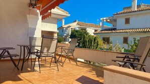 A terrace with outdoor furniture, a lamp, and a view of neighboring buildings.