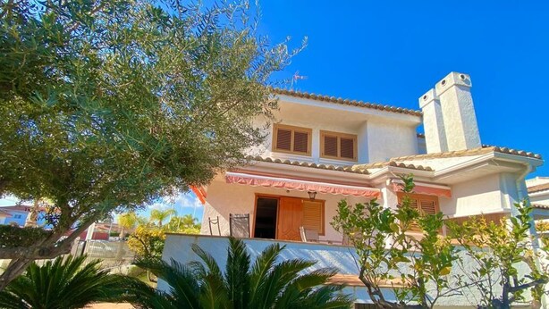 A two-story house with a tiled roof, a balcony, and a chimney.
