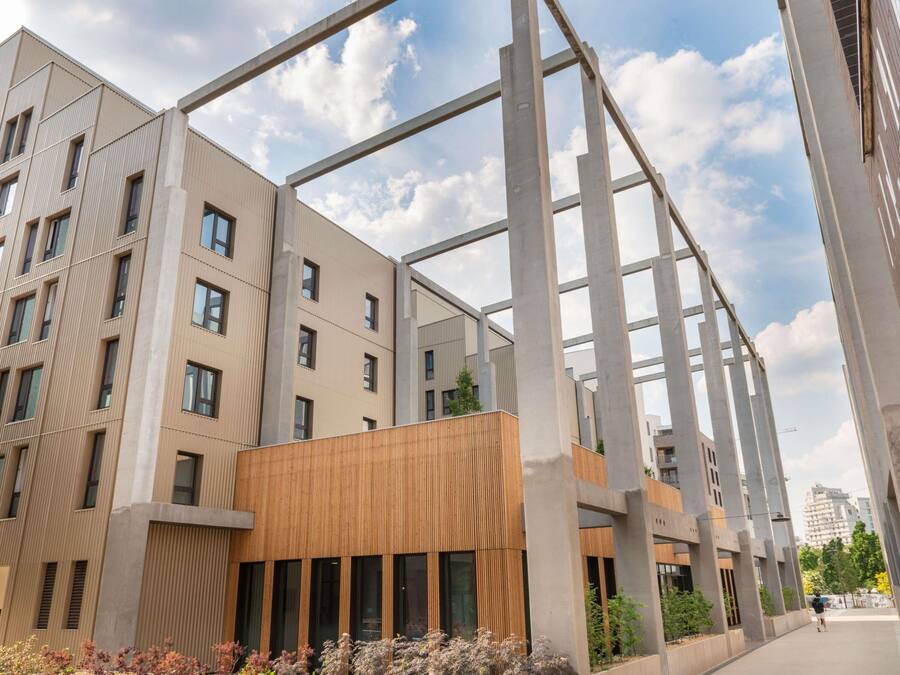 A modern building with a structural framework, large windows, and a flat roof.