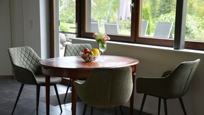 A dining area with a round table, two chairs, and a vase with flowers. - Vacations with a view of the Argen, an oasis of peace in the Argen Valley (Neukirch)