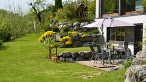 A modern house with a patio area featuring outdoor furniture and a stone wall. - Vacations with a view of the Argen, an oasis of peace in the Argen Valley (Neukirch)